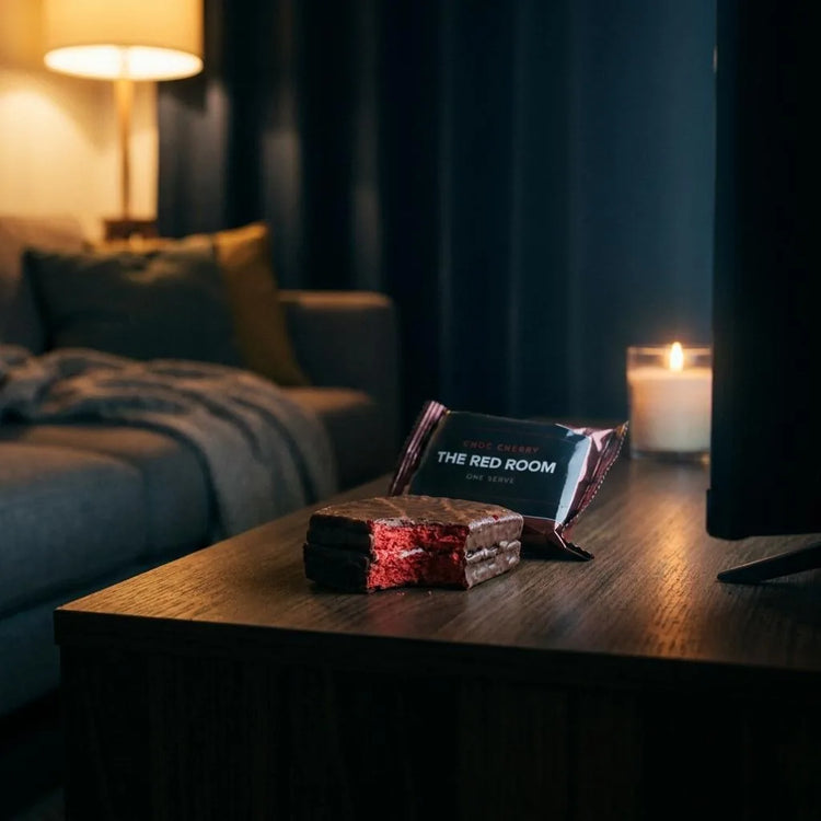 The Red Room choc-cherry snack from the Insidious Movie Night Box, bitten to show its red centre, on a side table by candlelight.
